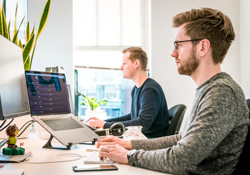 Two engineers working at desks with multiple monitors