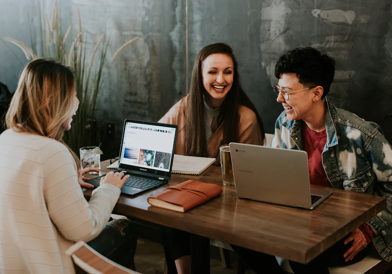 Three colleagues laughing while working together at a table