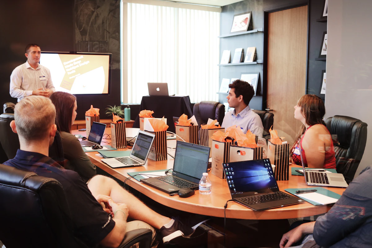 Team listening to a presentation in a boardroom with laptops open
