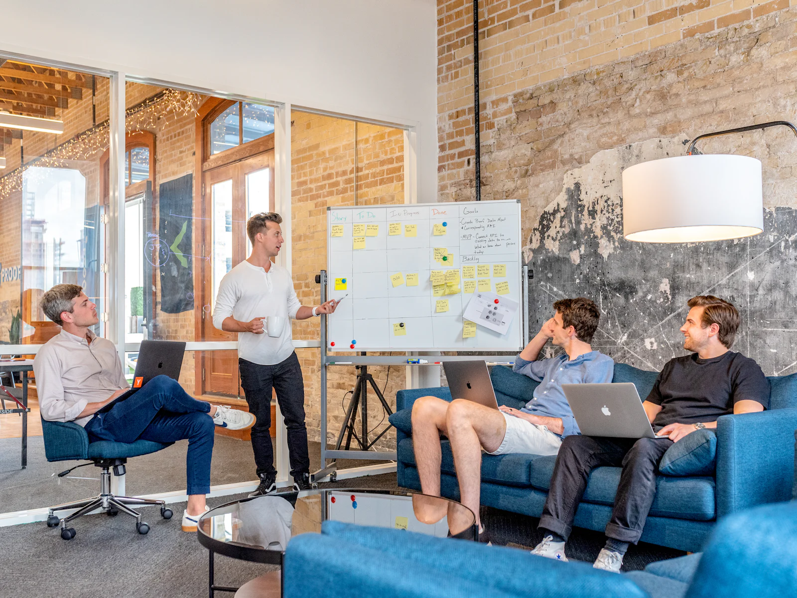 Team discussing ideas at a whiteboard in a brick-walled office