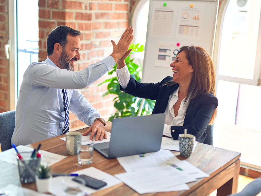 Two colleagues high-fiving at a desk