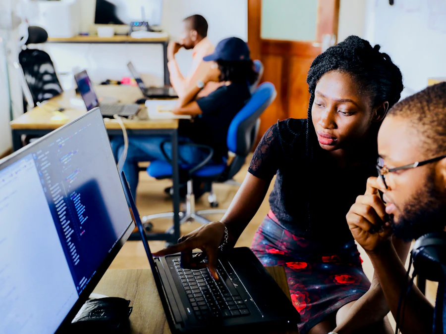 Two colleagues studying code together on a laptop screen